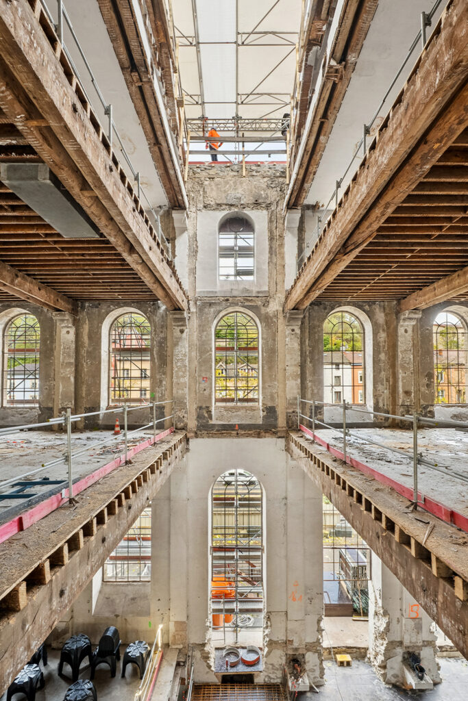 Photo intérieur depuis le premier étage de l'usine en travaux avec de belles fenêtres