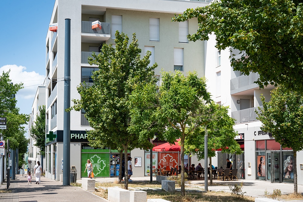 Place avec des commerces et une terrasse et des piétons