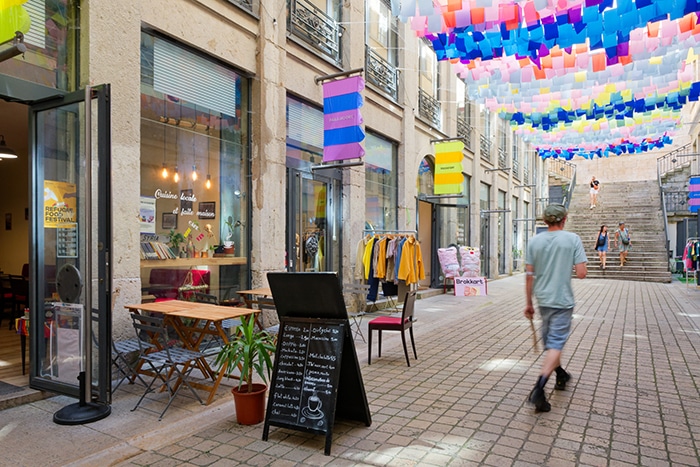 Photo du passage Thiaffait très colorées avec un passant devant des commerces et une terrasse extérieure